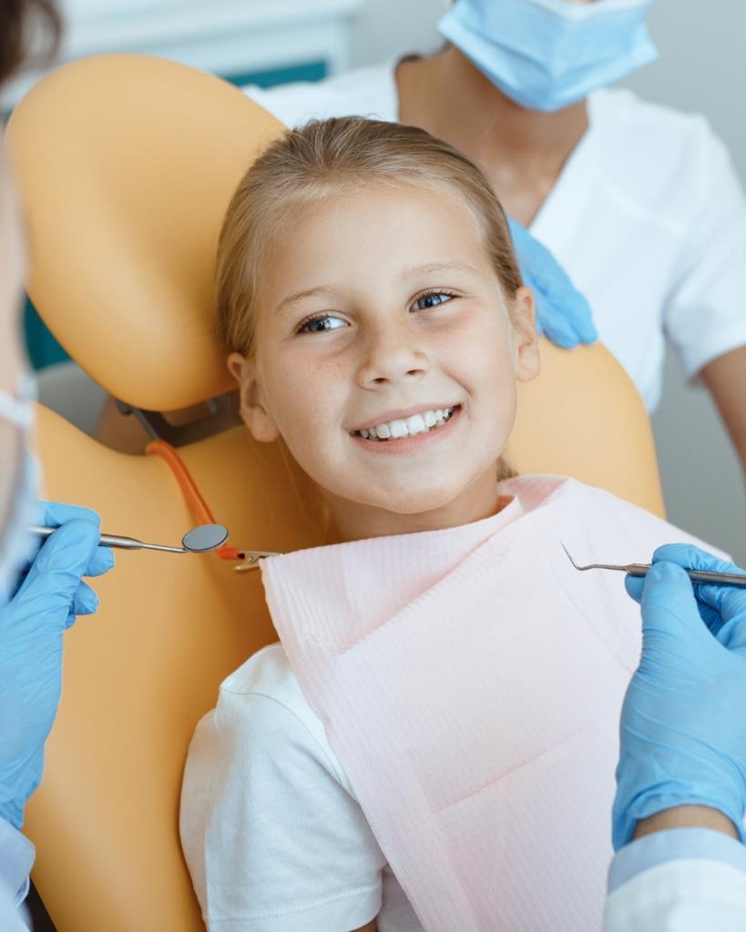 Niña sonriente en sillón dental